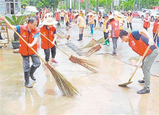 大雨过后，水浸过的路面积满黄泥和杂物，大批义工利用休息时间清理蓬江区建设路的淤泥与杂物。