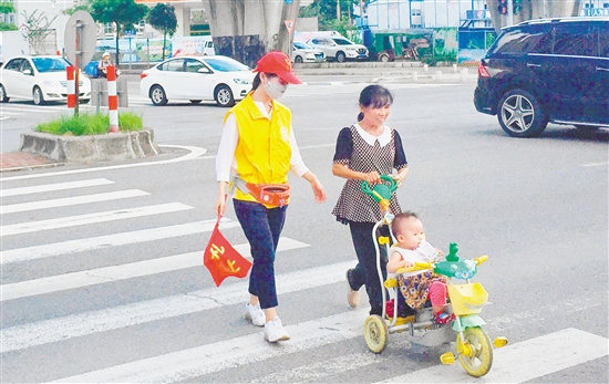 江海区一名志愿者引导市民安全过马路。